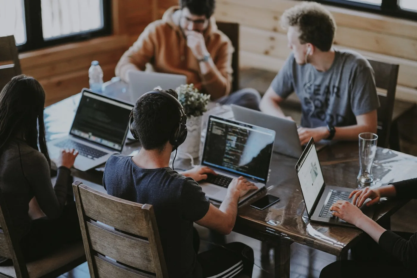 Équipe de travail autour d'une table, plusieurs ordinateurs portables ouverts