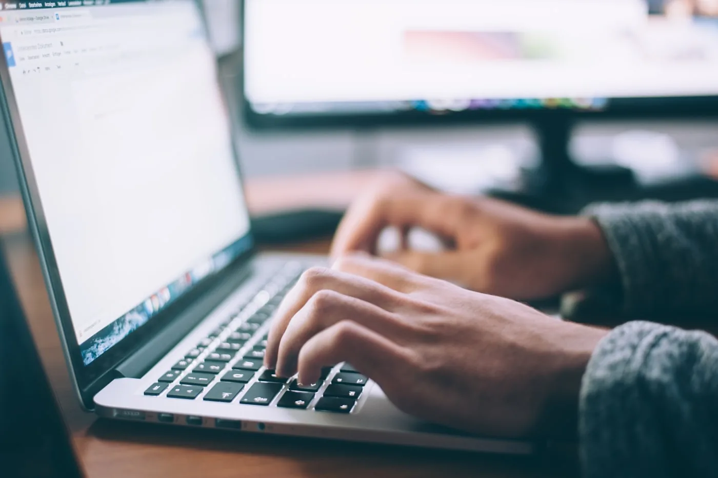 Mains sur le clavier d'un ordinateur portable, document ouvert à l'écran