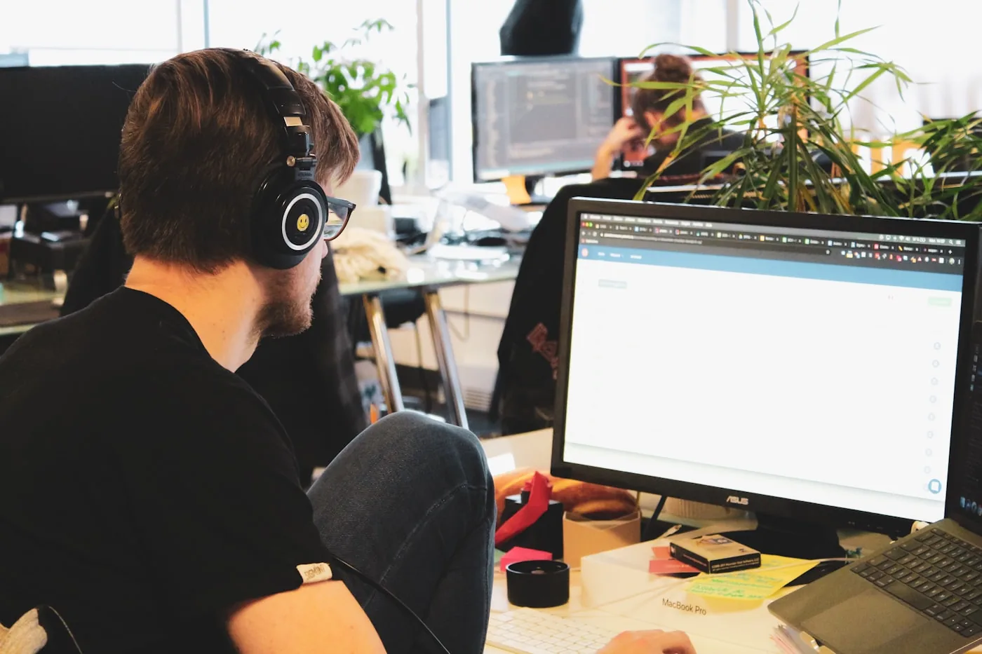 Technicien au casque devant son écran dans un bureau ouvert